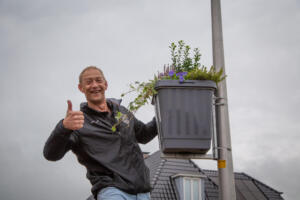 Man met plantenbak aan lantaarnpaal